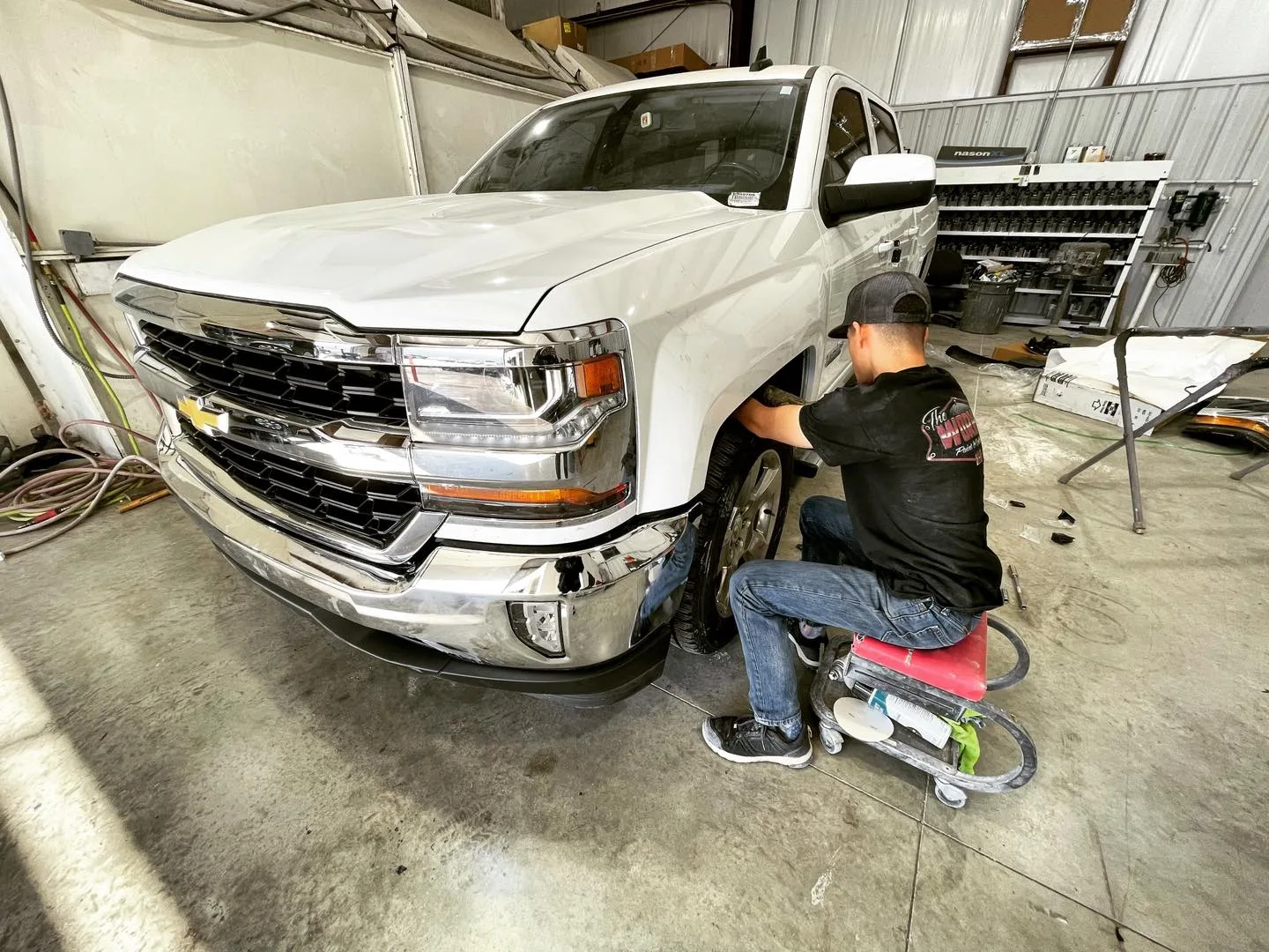 Technician working on a white pickup truck at The Works Paint and Collision in Oklahoma City